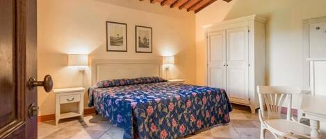 A bedroom with a bed, bedside tables, a desk, and chairs.
