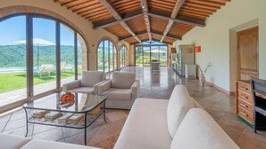 A spacious living area with a high ceiling, large windows, and a view of greenery. - Santo Pietro Resort (San Gimignano)