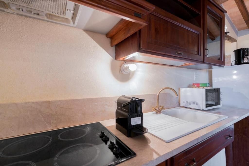 A kitchen with a stove, microwave, sink, and wooden cabinets.