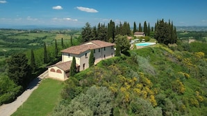 A villa with a tiled roof, surrounded by lush greenery and a clear view of the countryside. - Santo Pietro Resort (San Gimignano)