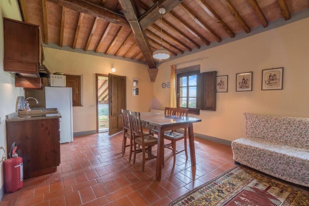 A rustic kitchen with a dining table and chairs, a sofa, and a patterned rug.