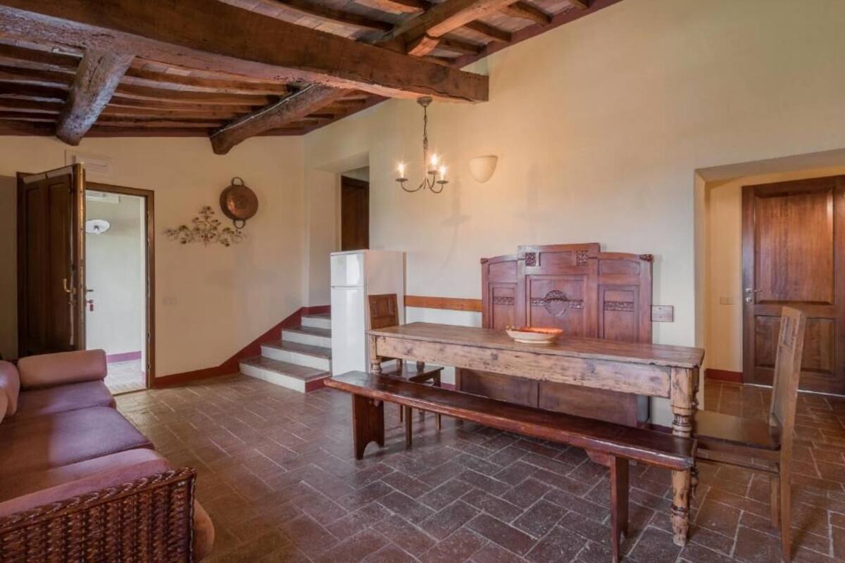 A rustic interior with a wooden table, bench, and a chandelier.