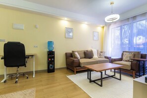 Uma sala de estar moderna com sofá, mesa de centro, cadeira de escritório preta e purificador de água.