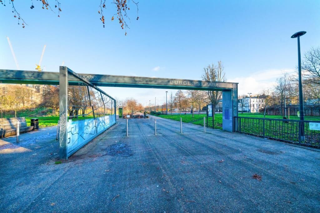 A pedestrian bridge with the inscription "BURGESS PARK" and a metal fence on one side.