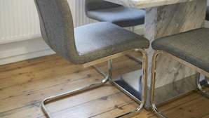 A dining table with a marble top and two grey upholstered chairs with metal legs. - Welcoming 1-bedroom apartment in the heart of London (London)