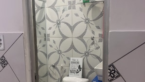 Ein Badezimmer mit gemusterten Fliesen, einer Toilette mit braunem Sitz und einem Schild an der Wand.