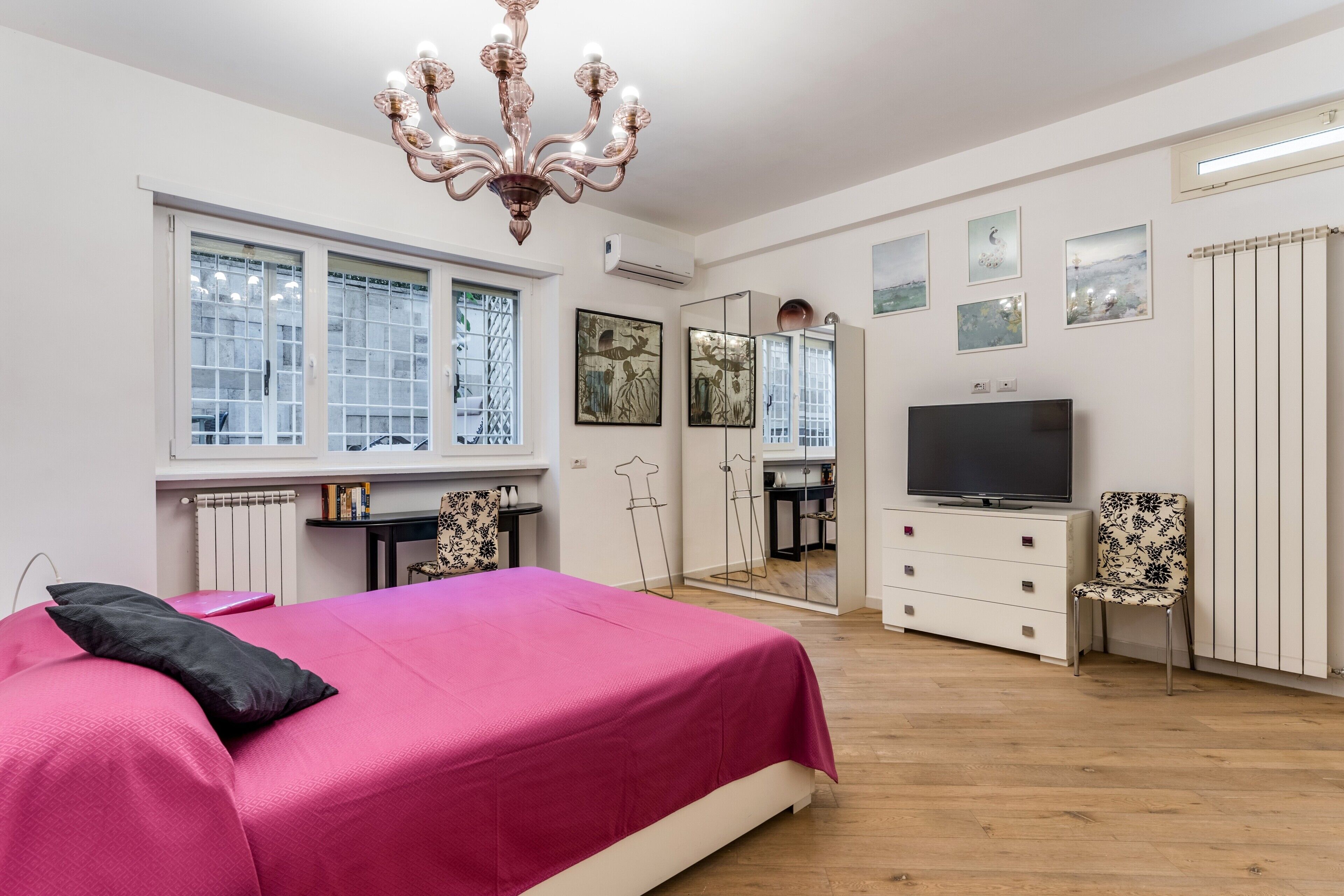 Un dormitorio con una cama grande, un televisor, un aparador y una silla.