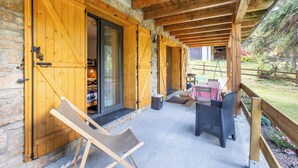 A covered outdoor seating area with a stone wall, wooden beams, and a view of a garden. - Family cocoon for nature lovers overlooking the forest. (Occitanie)