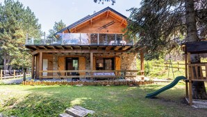 A wooden cabin with a balcony, a stone foundation, and a playground area. - Family cocoon for nature lovers overlooking the forest. (Occitanie)