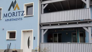 A multi-story building with a blue facade and a sign reading "MORITZ APARTMENTS".