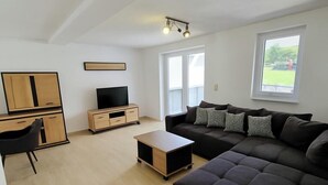 Una sala de estar moderna con un sofá, un televisor y un escritorio.