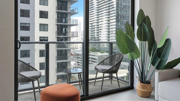 Een balkon met twee stoelen, een tafeltje en een grote plant.