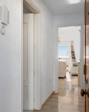 Ein Flur mit Holzboden, der zu einem Schlafzimmer mit Bett und Fenster führt.