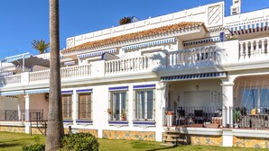 A two-story building with a white facade, blue window frames, and a tiled roof. - Arkadia Beach apartment (Mijas)