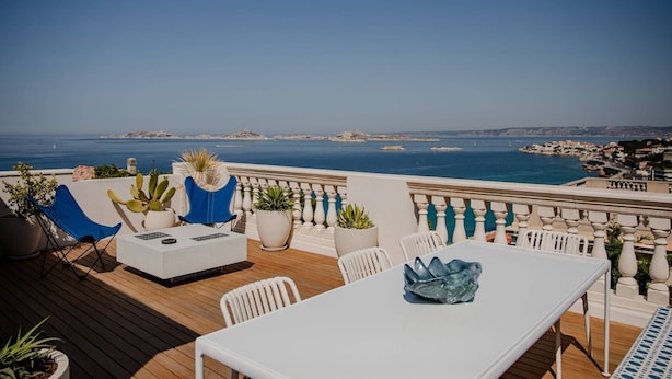 A terrace with a white table and chairs, potted plants, and a view of the sea. - MAISON DOMINOS Villa Pâquerette avec Piscine, Marseille (Marseille)