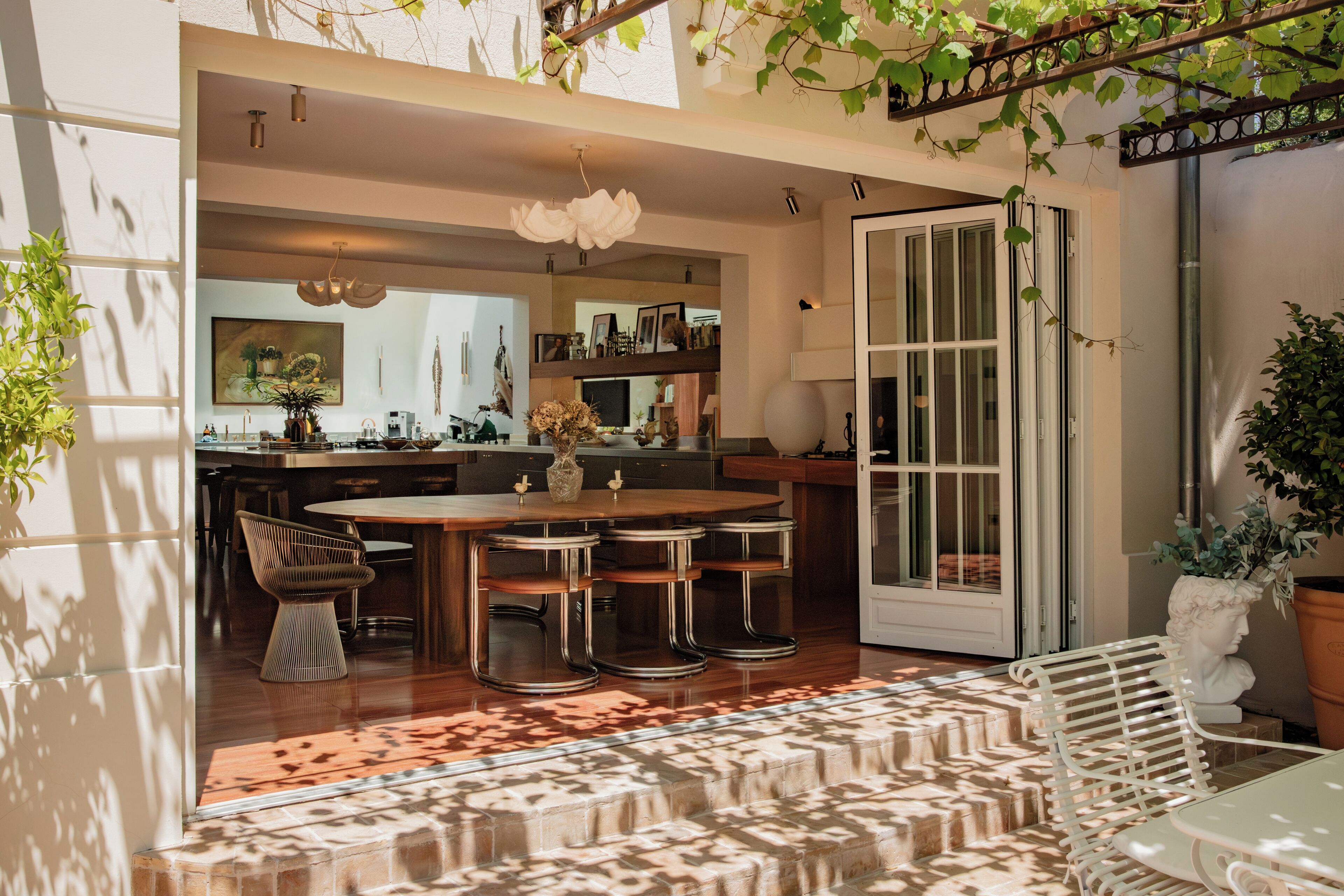 Una cocina moderna con una isla central, taburetes de bar y un comedor con alfombra estampada.