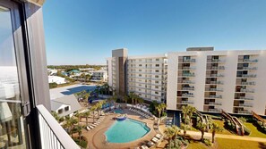A hotel with multiple floors, a central swimming pool, and a landscaped courtyard with palm trees. - Beautiful Inside and Out Mainsail 276 (Miramar Beach)