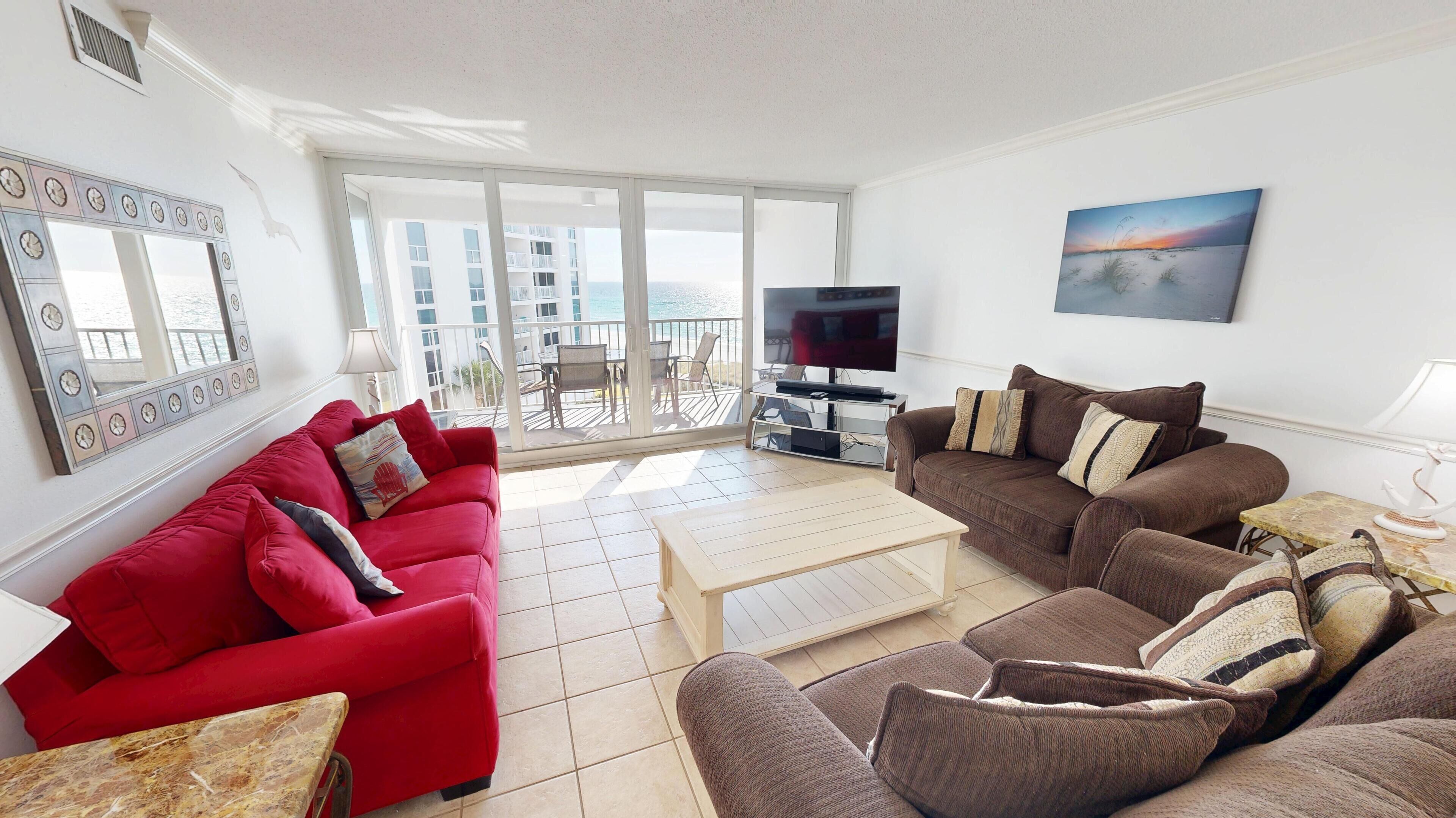 Sala de estar com dois sofás, uma mesa de centro, televisão e varanda com vista.