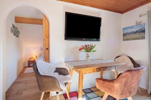 A dining area with a table, chairs, a TV, and a painting on the wall. - Apartment 'Haus Bergliebe - Zugspitzblick' with Mountain View, Balcony and Wi-Fi (Pfronten)