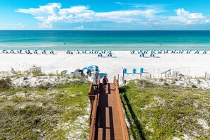 A beach with a wooden boardwalk leading to the shore, white sand, and clear blue water. - Spacious Island Princess 607 w/Seasonal Beach Service (Fort Walton Beach)