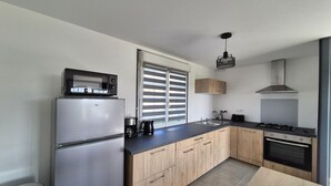 Une cuisine moderne équipée d’un réfrigérateur, d’une cuisinière, d’un four à micro-ondes et de meubles de rangement en bois.