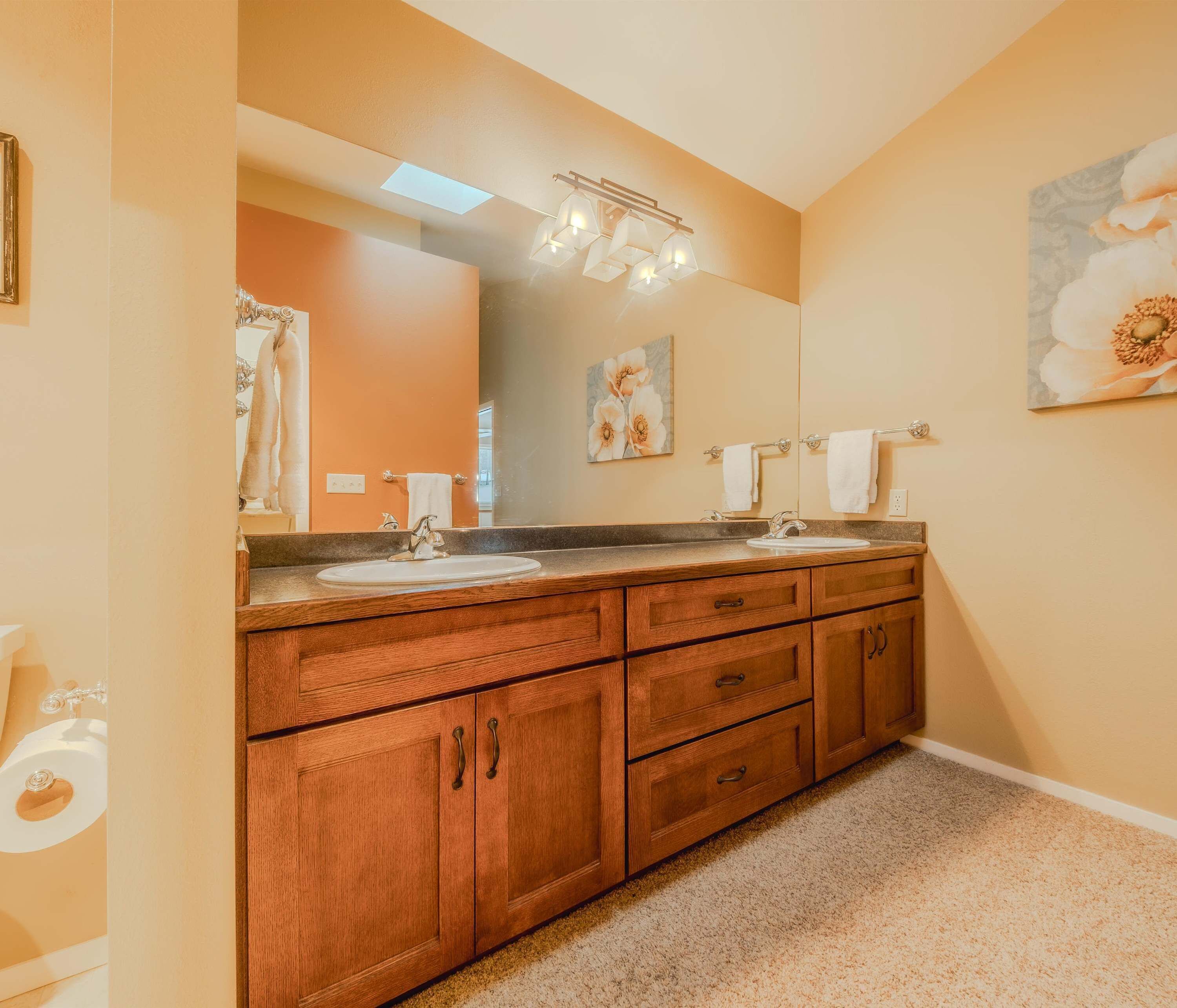 Une salle de bain avec des meubles en bois, un double vasque et un grand miroir.
