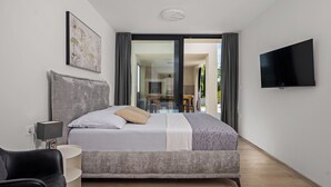 Een moderne slaapkamer met een groot bed, een televisie en uitzicht naar buiten.
