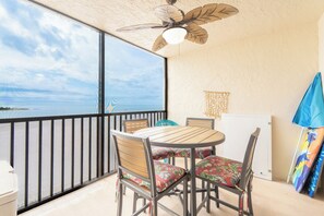 A balcony with a table and chairs, a ceiling fan, and a view of the sea. - 🌊Beachfront with Great Gulf Views | Easy Beach Access | Carlos Pointe #624⛱️ (Fort Myers Beach)