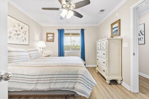 A bedroom with a bed, a dresser, a ceiling fan, and a window with curtains. - Carolina Yacht Landing 16 (Little River)