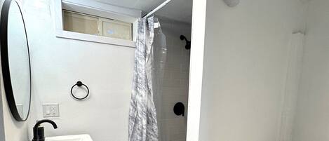 Un baño con lavamanos, inodoro y ducha blancos.