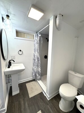A bathroom with a white sink, toilet, and shower.