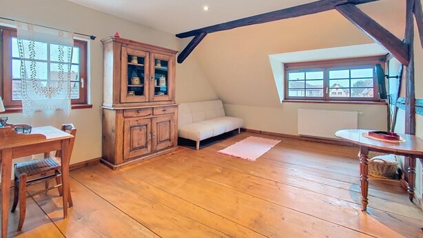 A room with wooden flooring, a dining table with chairs, a cabinet, a sofa, and a window with a view. - La Perle du Ried n°9 - Alsatian charm between Strasbourg, Colmar and Europapark (Boofzheim)