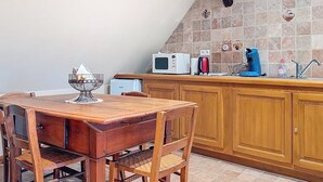A kitchen with a wooden table and chairs, a microwave, and a coffee maker. - La Perle du Ried n°9 - Alsatian charm between Strasbourg, Colmar and Europapark (Boofzheim)