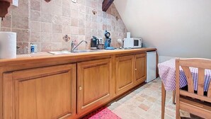 A kitchen with wooden cabinets, a tiled backsplash, a microwave, a coffee maker, and a small sink. - La Perle du Ried n°8 - Alsatian charm & serenity, just a stone's throw from Europa-Park (Boofzheim)