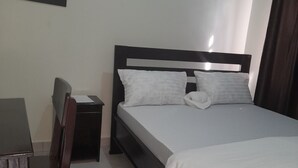 A bedroom with a bed, a chair, a nightstand, and a wall-mounted picture. - Origin Ventures Hostel (Moshi)