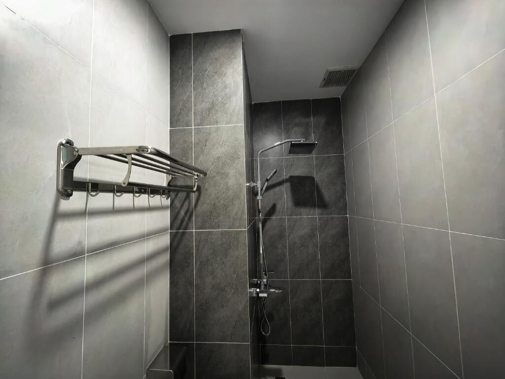 Un baño moderno con azulejos grises, una ducha con cabezal de ducha manual y un perchero para toallas.