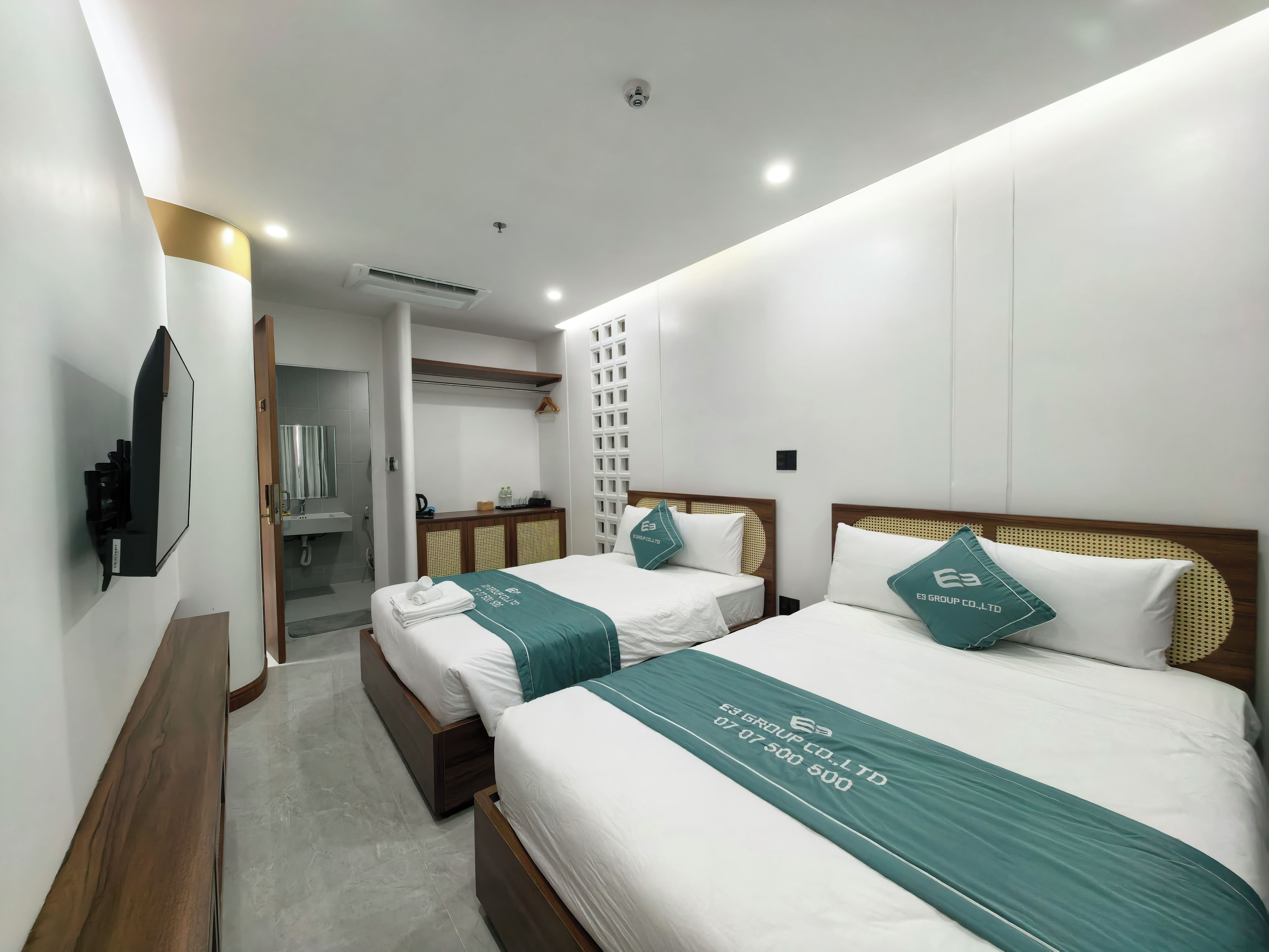 Habitación de hotel con dos camas, un televisor y un baño a la vista.