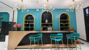 Una zona de recepción con una decoración azul aguamarina, tres ventanas arqueadas, un mostrador de recepción y tres taburetes azul aguamarina.