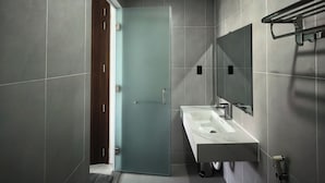 Un baño moderno con un espejo grande, un lavabo y una puerta que da a otra habitación.