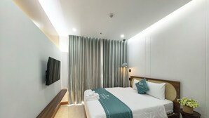 Une chambre d’hôtel moderne avec un lit en bois, un téléviseur à écran plat fixé au mur et une grande fenêtre avec des rideaux.