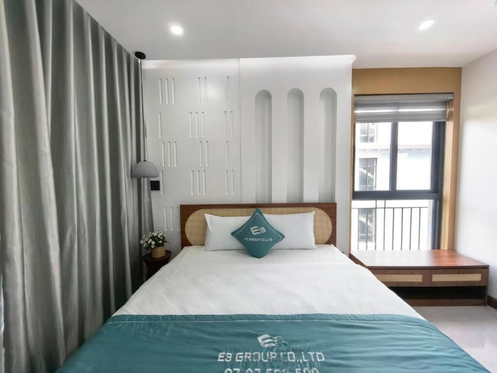 Camera d'albergo con un letto, un comodino, una lampada, una finestra con persiane e vista sull'esterno.