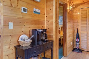 Ein Holzblockhaus-Innenraum mit Kaffeemaschine, Korb und Staubsauger.