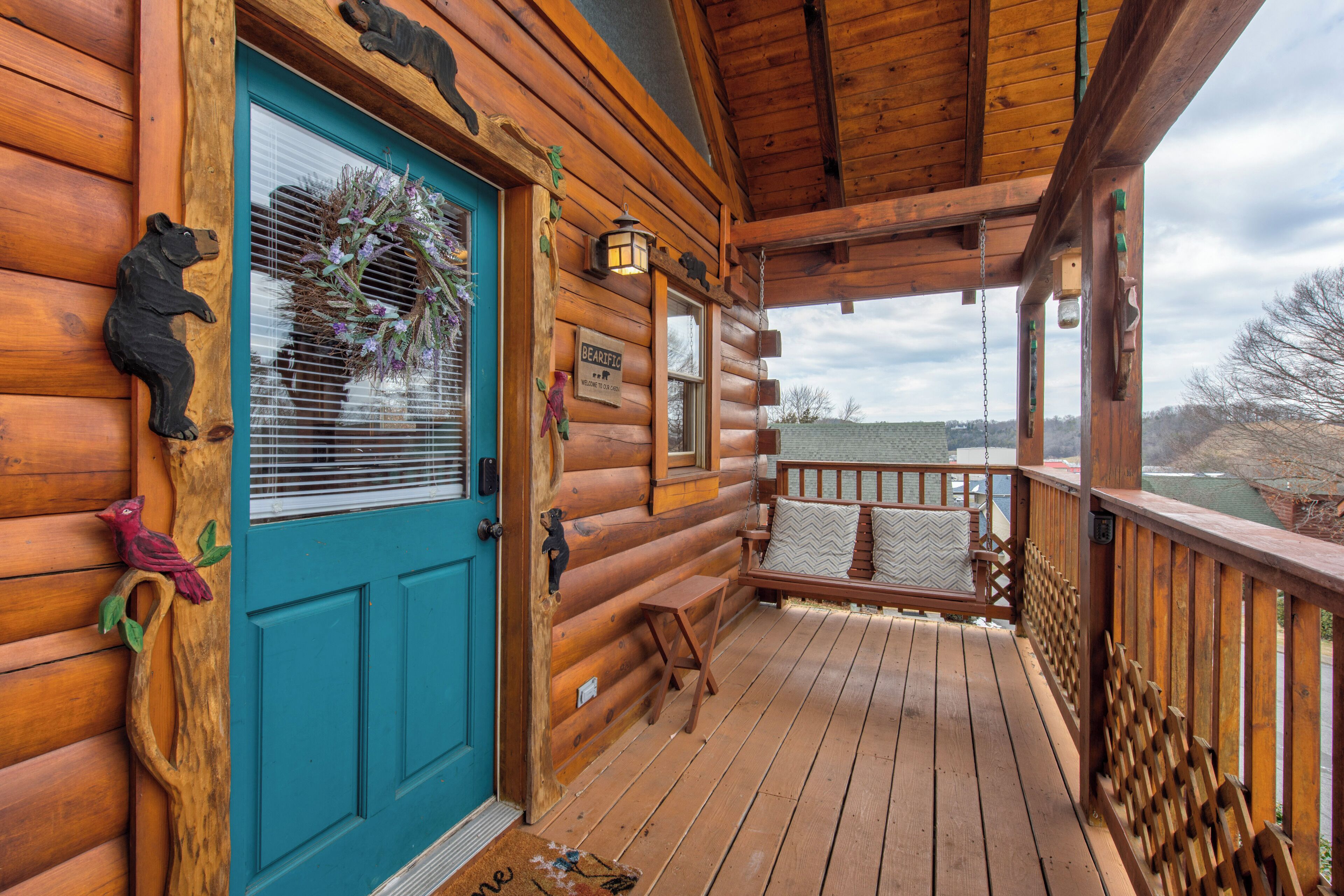 A wooden cabin with a blue door, a porch with a bench, and a view of the surrounding landscape.