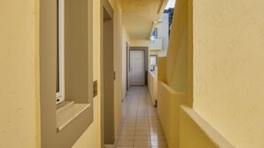 A narrow hallway with yellow walls and a tiled floor, leading to a door at the end. - Sunny Vibes Stalis by Estia (Stalida)