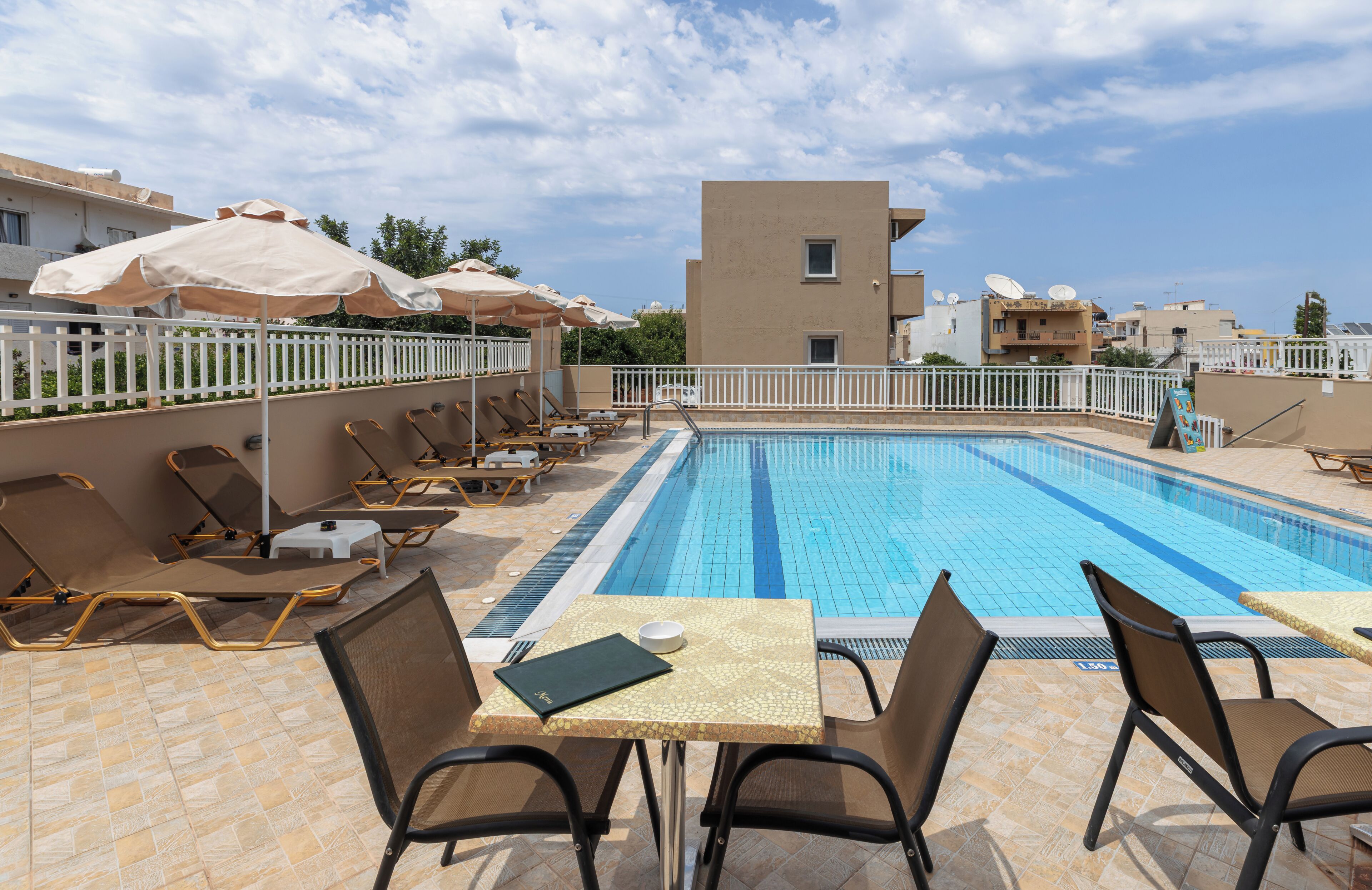A pool area with lounge chairs, umbrellas, and a table with a book and a cup.