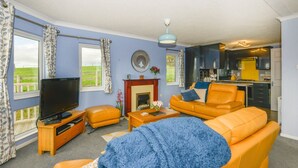 Ein Wohnzimmer mit Fernseher, einem orangefarbenen Sofa und einem Kamin.