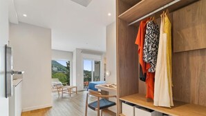 A modern room with a wooden floor, a desk, a chair, and a wardrobe with hanging clothes. - L'Hostalet de Cabrils (Cabrils)