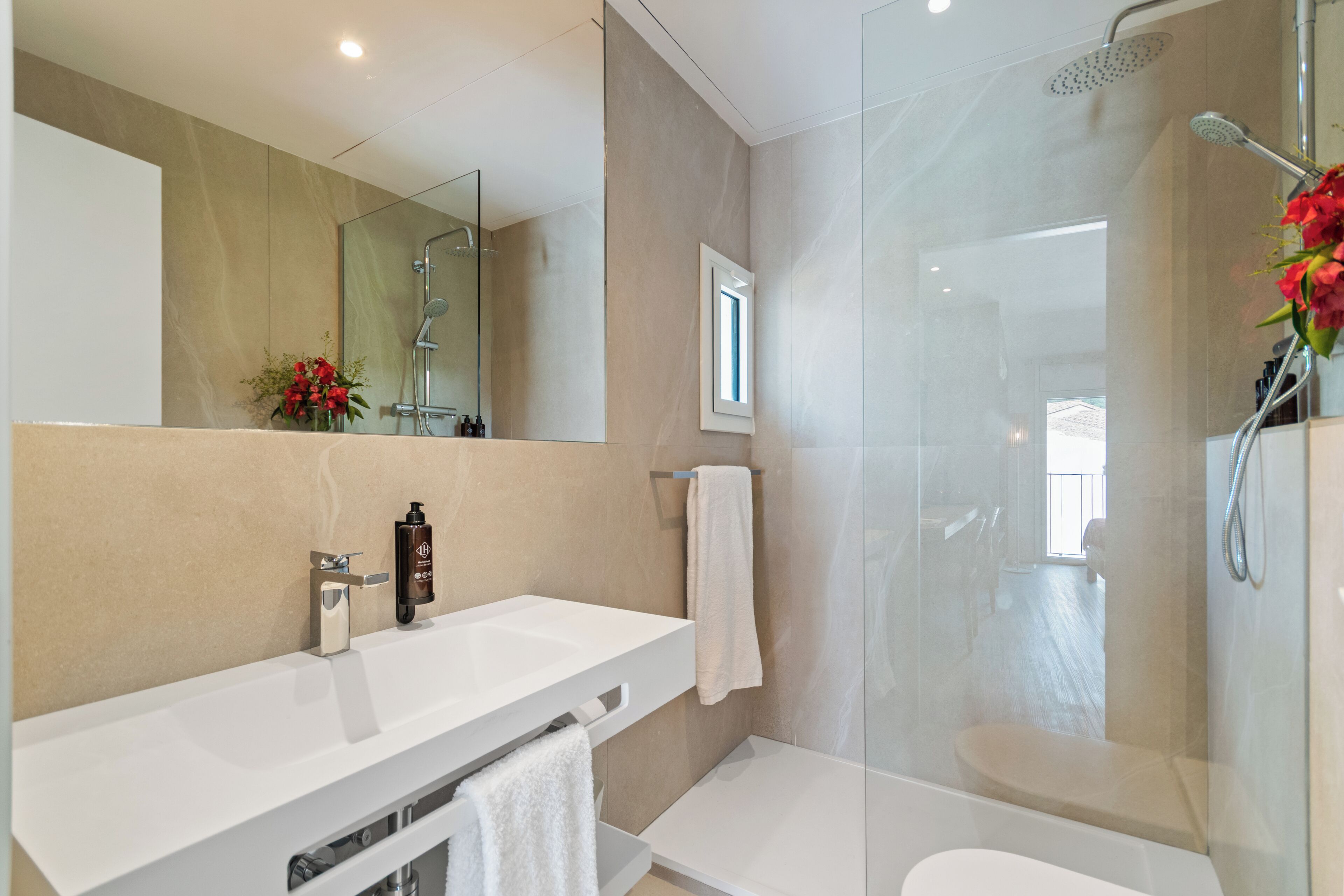 A modern bathroom with a glass-enclosed shower, a white sink, and a mirror.