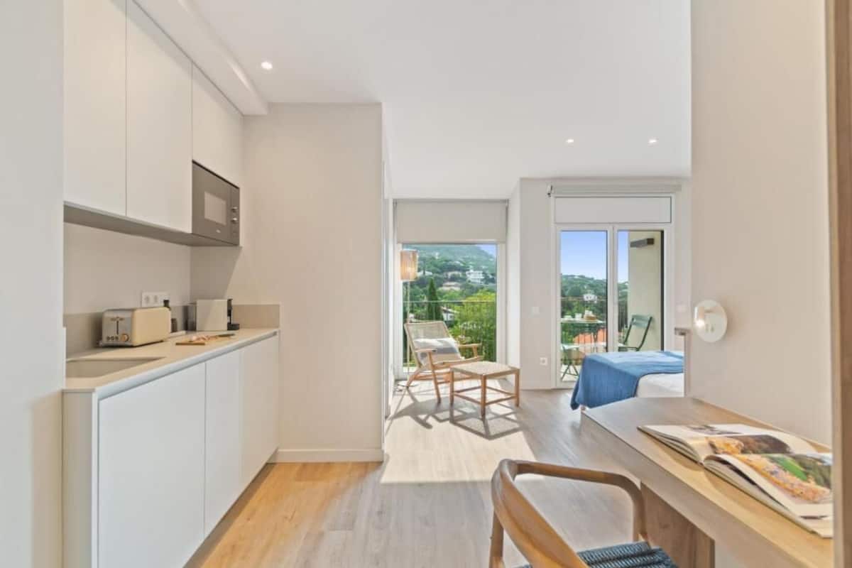 A modern kitchen with white cabinets, a built-in microwave, and a small dining area with a table and chairs.