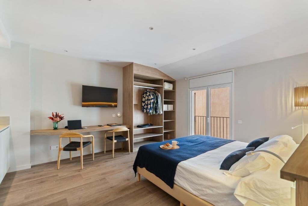 Ein modernes Schlafzimmer mit Bett, Schreibtisch, Stuhl, Fernseher und Kleiderschrank.